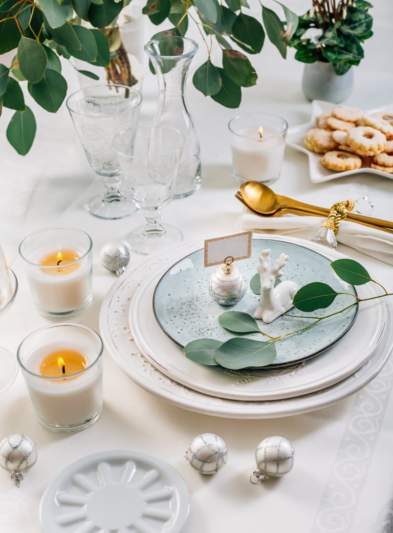 Christmas table setting with eucalyptus, cutlery and candles in white and green tone